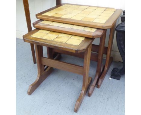 A modern nesting set of three teak, ceramic tile topped tables, raised on trestle ends and platform feet&nbsp; largest 18"h&n