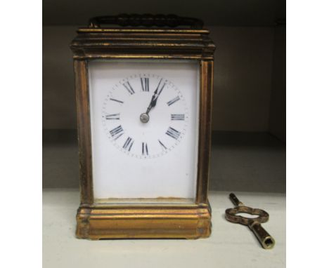 An early 20thC lacquered brass cased carriage clock with bevelled glass panels and a folding top handle; the gong strike move