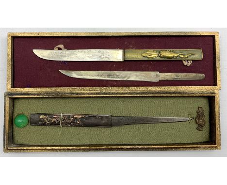 Two Japanese Meiji Kozuka, the first decorated in high relief with Samurai figures in mixed metals with gilt highlights, the 