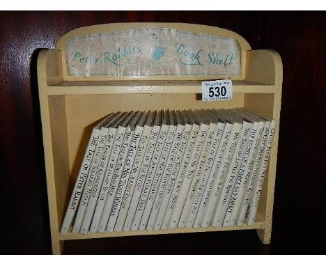 23 Beatrix potter books on a painted book shelf.