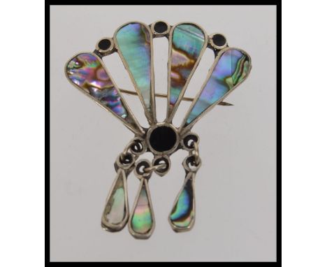 An white metal brooch with inset abalone shell and black enamel in the shape of a peacocks tail with inset abalone dangles, M
