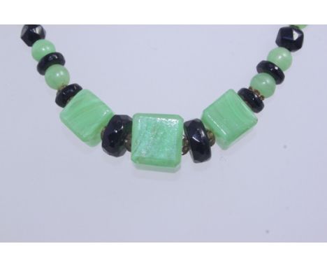 A 1930s Art Deco glass bead necklace with green square cut,round and faceted black glass beads with round claw clasp. Measure