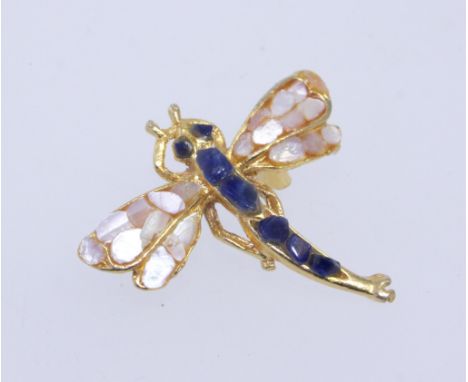 A vintage yellow metal brooch in the form of a dragonfly set with mother of pearl and blue gem stones with roller clip clasp.