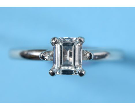 A platinum ring, set an emerald cut solitaire diamond, approx. ring size Q  See colour illustration 