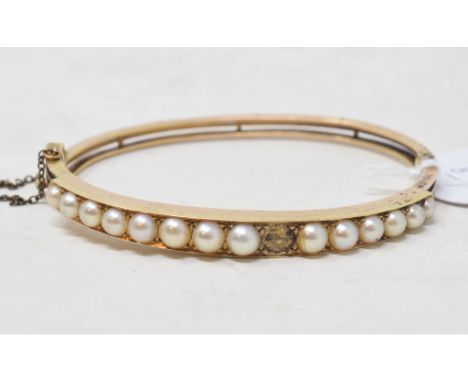 EXTRA LOT: An Edwardian yellow coloured metal and seed pearl bangle, lacks one seed pearl, apparently unmarkedReport by RB14.