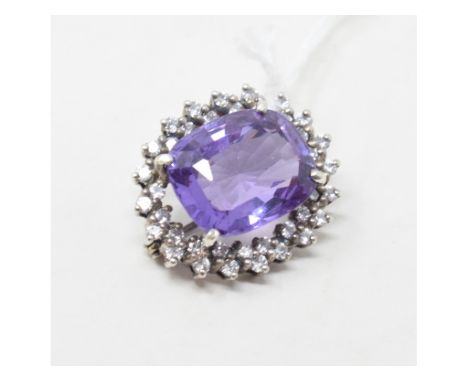 An oval brooch, set a central amethyst within a surround of diamonds 