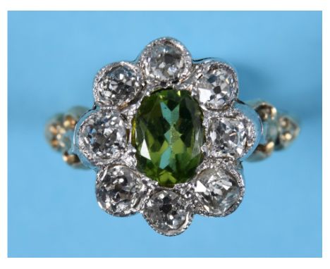 A gold cluster ring, the central old cushion cut peridot within a surround of eight diamonds, approx. rings size M½ See colou