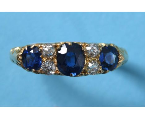 A yellow coloured metal ring, set three natural sapphires interspersed by four diamonds, approx. ring size S See illustration