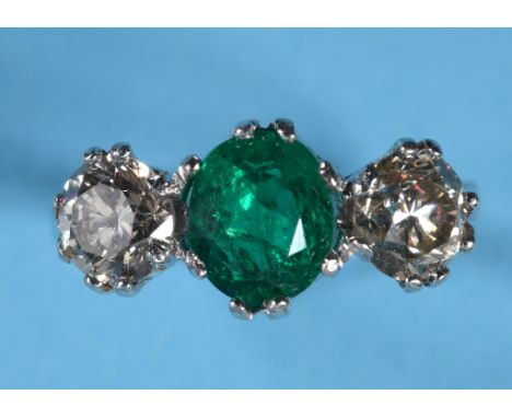 An 18ct white gold ring, the central oval emerald within two diamonds, approx. ring size M See illustration 