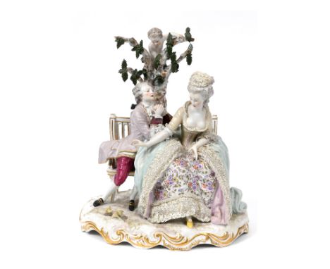 A late 19th century Meissen porcelain group, the proposal, the figures on a garden bench, by a tree with a putto, 29 cm high 