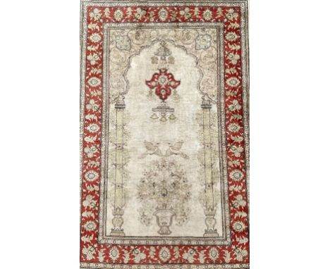 A SILK HEREK PRAYER RUG, TURKISHThe ivory mehrab with a vase of flowers supported by single columns rising to a pale pink arc