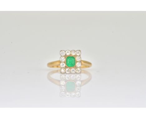 A GOLD, EMERALD AND DIAMOND RECTANGULAR CLUSTER RINGMounted with a cut cornered rectangular step cut emerald at the centre, i