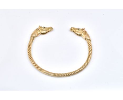 A 9CT GOLD HORSES HEAD BANGLEIn a twist oval design, with horse head terminals, having gem set eyes, London 1997, gross weigh