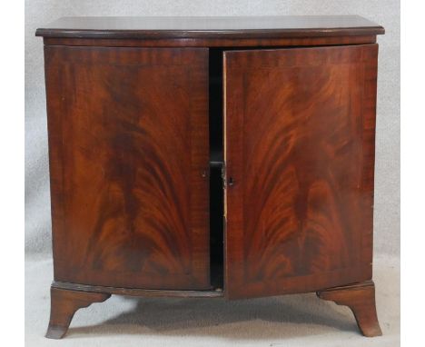 A Georgian style flame mahogany bowfronted side cabinet fitted with crossbanded panel doors on swept bracket feet. H.79 W.84 