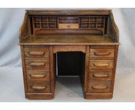 A 19th century oak roll top desk with S shaped tambour front enclosing interior fitted with numerous pigeon holes above two b