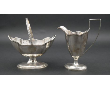 A Victorian silver handled sugar bowl and cream jug with linear detailing around the scalloped rim and on the handle of the s