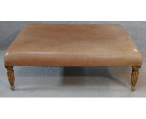 A 19th century style hearth stool in light tan leather upholstery on shaped reeded supports. H.42 L.122.5 W.93cm 