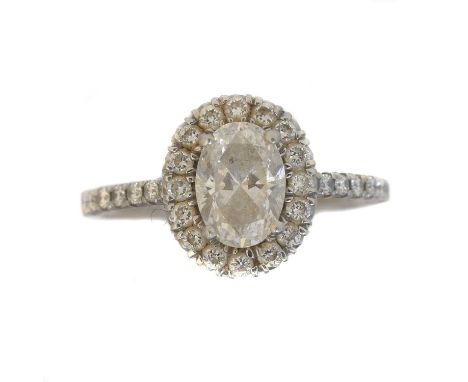 A platinum diamond halo cluster ring. The oval cut diamond weighing 0.92ct within a brilliant cut diamond surround and simila