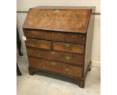 An early 18th Century walnut bureau, the four panel top cross-banded over a cross-banded fall front opening to reveal a fitte