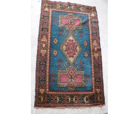 A Caucasian rug with centre lozenge medallion within two further geometric medallions on a turquoise ground, within a red, tu