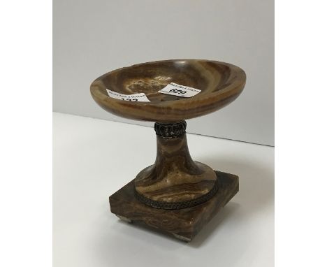 A brown onyx urn with silvered metal embellishments/banding on tapered feet, 14 cm high, together with a modern bronze wall h