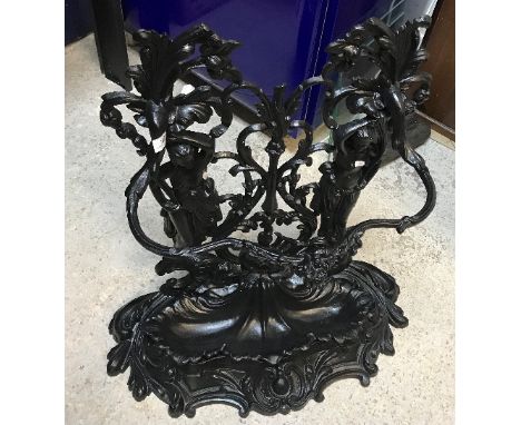 A Victorian style cast iron black painted stick stand, the two maidens holding aloft foliate branches and bearing label inscr