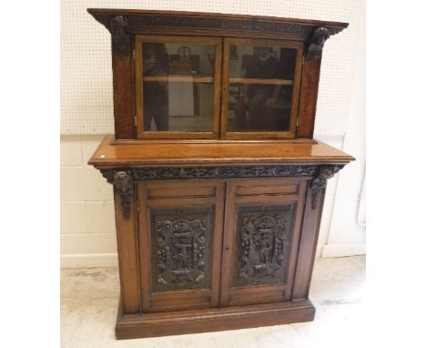 A late 19th Century oak buffet, the plain top above a carved frieze decorated with hunting scene flanked by mask corbels over