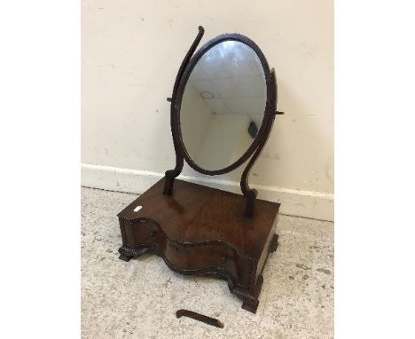A 20th Century mahogany serpentine fronted toilet mirror with oval plate, the fitted drawer with various compartments raised 