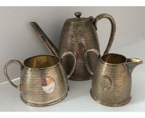 A plated tea service comprising teapot, twin handled sugar and milk jug with textured decoration and empty cartouches, teapot