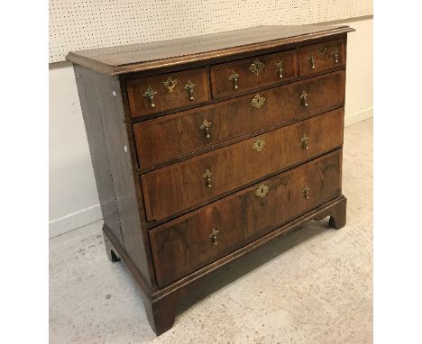 An early 18th Century walnut chest, the cross-banded top with moulded edge above three short and three long graduated drawers
