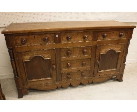 A 19th Century North Country oak and inlaid enclosed dresser, the plain top with applied moulded edge over three drawers and 