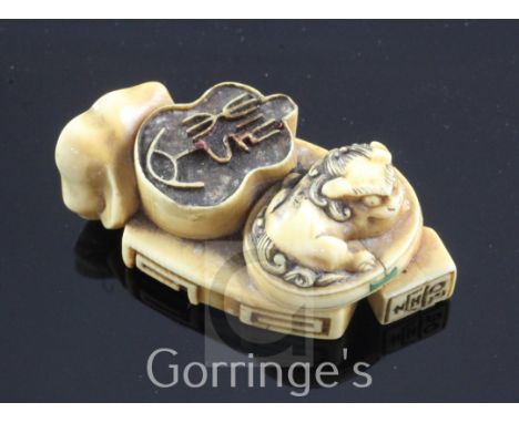 A Japanese ivory multi seal netsuke, 19th century, carved in relief with a shi-shi, seated amid multiple seals, carved in rel