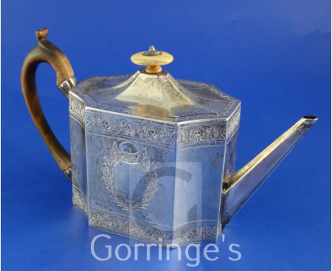 A George III bright cut engraved silver teapot, of rectangular form with inswept corners, decorated with foliate bands and tw