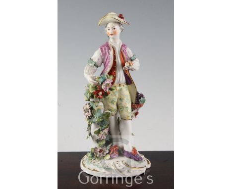 A Derby figure of a fruit seller or gardener, c.1765, standing by a flower encrusted tree stump supporting a basket of grapes