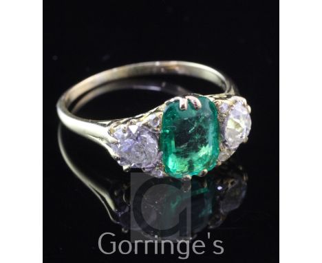 A Victorian style 18ct gold, three stone emerald and diamond ring, the central emerald weighing approximately 1.72ct and flan