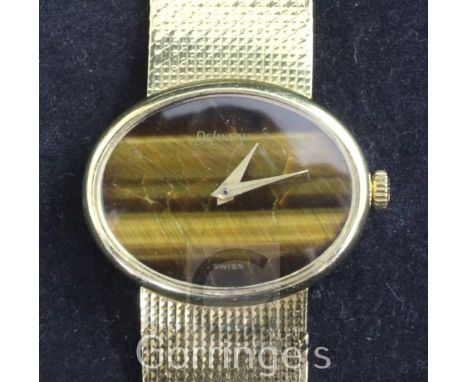 A lady's 1960's DeLaneau 18ct gold manual wind dress wrist watch, with blind oval tiger's eye quartz dial, on integral 18ct g