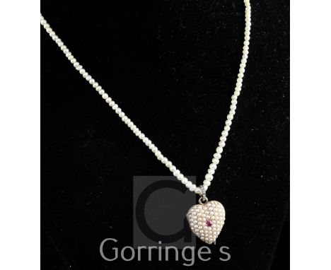 An early 20th century gold, ruby and split pearl set heart shaped pendant locket, with rose cut diamond set bale, suspended f