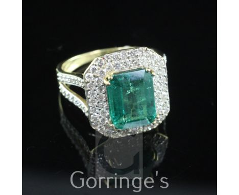 An 18ct gold, emerald and diamond cluster dress ring by Lorique, of octagonal form, the central emerald weighing 3.06ct and b