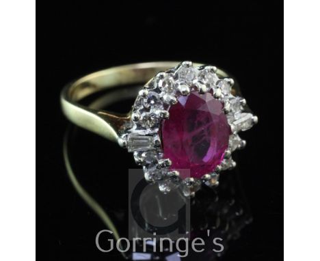 An 18ct gold, ruby and diamond oval cluster ring, the oval cut ruby weighing approximately 1.50-2.00ct and bordered by round 