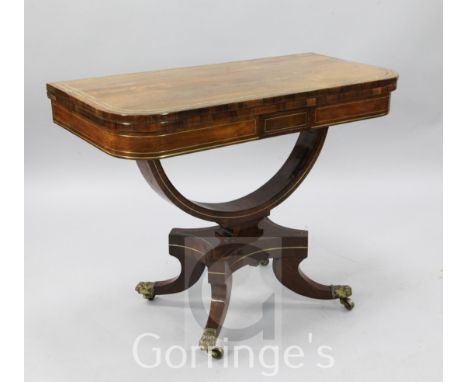 A Regency brass strung rosewood card table, with folding D shaped top and U shaped stem, on downswept legs, fitted brass caps