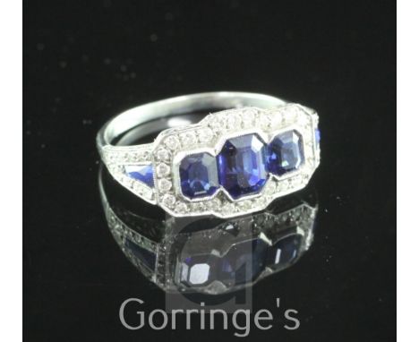 A white gold three stone sapphire and diamond cluster ring, with sapphire and diamond set shoulders, size M.