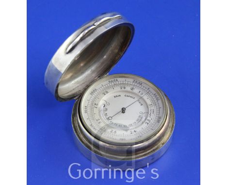 A late Victorian silver cased brass pocket barometer, of circular form, the hinged lid engraved with armorial and motto, make