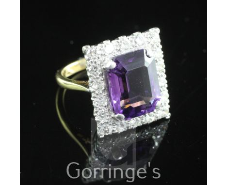 An 18ct gold and platinum, amethyst and diamond tablet ring, set with emerald cut amethyst within a round cut diamond set bor