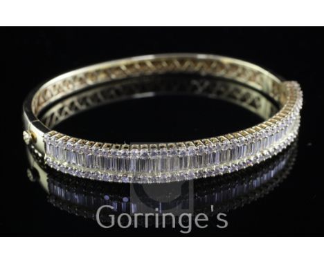 An 18ct gold and diamond hinged bangle, with seventy channel set baguette cut diamonds and brilliant set border.