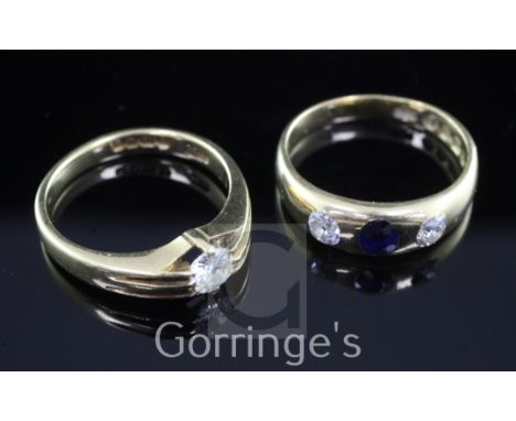 A late Victorian 18ct gold and gypsy set three stone sapphire and diamond ring and an Edwardian 18ct gold and claw set solita