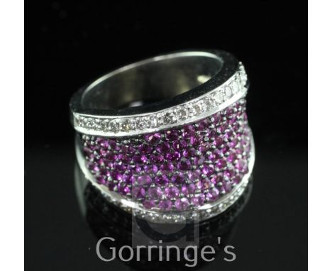 A modern white gold and pave set ruby dress ring with brilliant cut diamond set borders, size M.