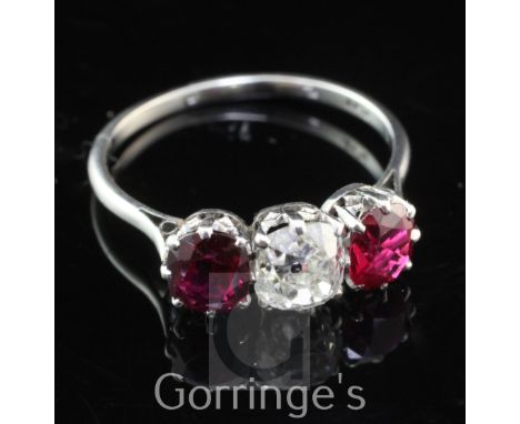 An early 20th century platinum and three stone ruby and diamond ring, the cushion cut diamond flanked by two similar cut rubi