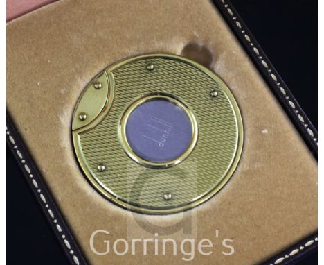 A cased Dunhill gold mounted stainless steel cigar cutter, of circular form, the front and back with engine turned decoration