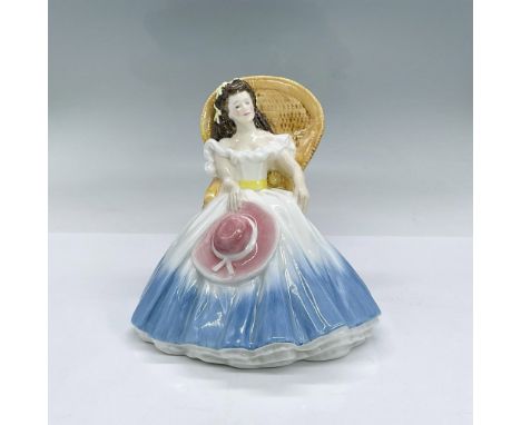 Glazed bone china figure of lady seating in a wicker chair wearing a white and blue dress accented with a yellow waist sash a