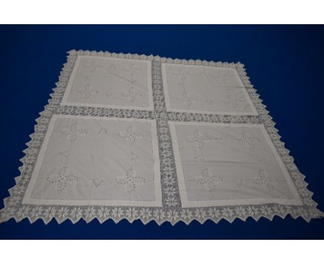 An antique white bed cover, having raised floral embroidery, cutwork edged in pale pink, ladder work and deep crochet edging.